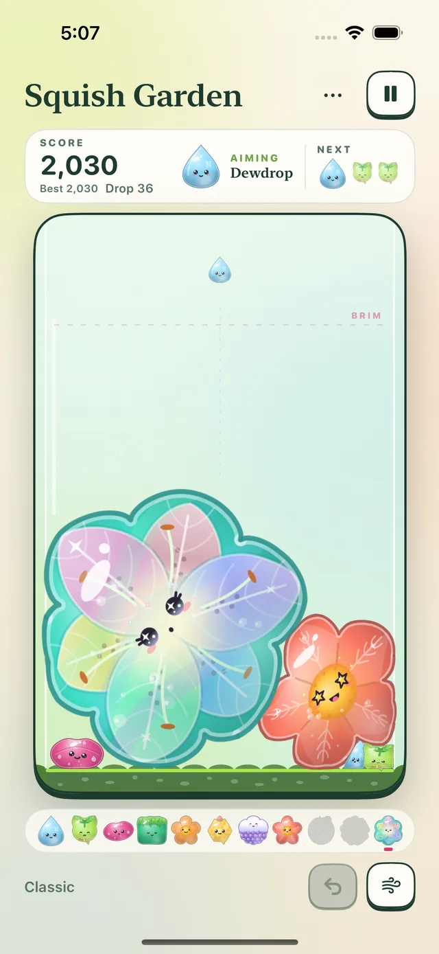 Squish Garden on iPhone: a glass jar where a giant rainbow bloom and a coral jelly rest on the moss, with a small jelly waiting to drop.